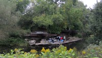 View of the pavilion from above; people gather near the water